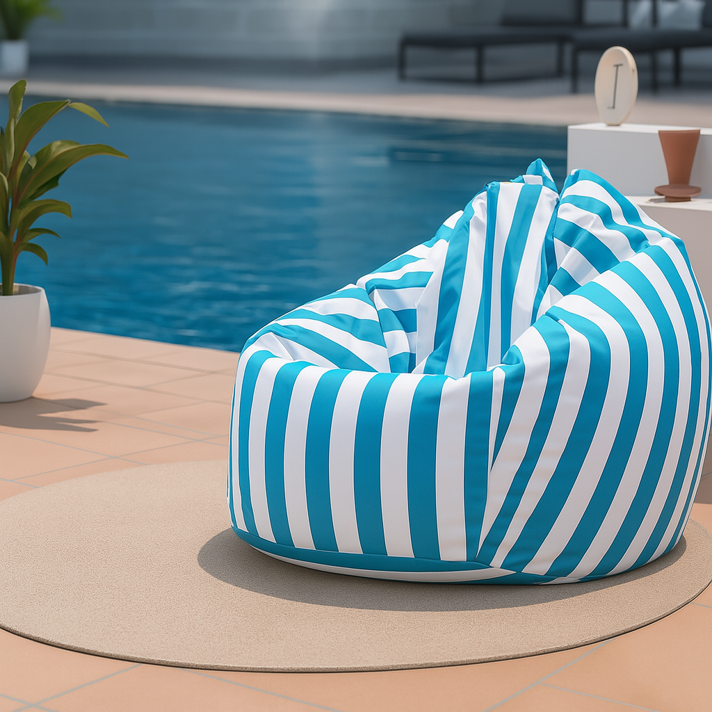 Outdoor poolside scene with a sky blue and white striped teardrop bean bag on a beige mat next to a clear blue pool.