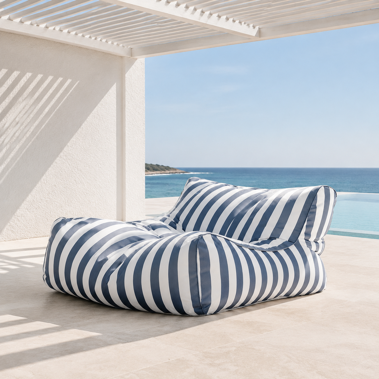 Dust blue and white striped Big Chill King weatherproof outdoor bean bag lounger in a coastal setting