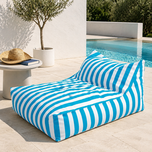 Sky blue and white striped Big Chill weatherproof bean bag lounger beside a Mediterranean pool on a pale stone terrace.