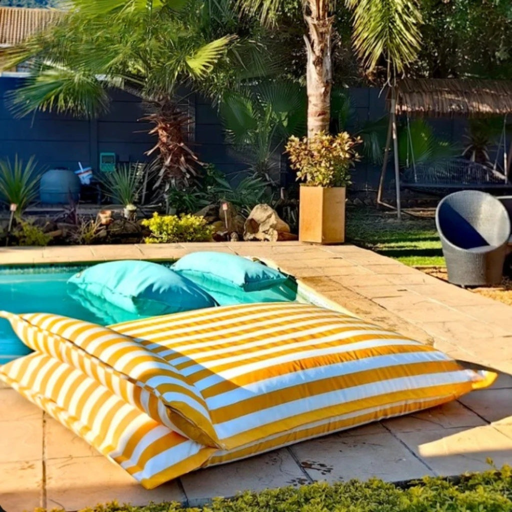 Collection image showing the Big Bertha double floating beanbag lounger cover in yellow and white stripe, displayed on an outdoor poolside deck.