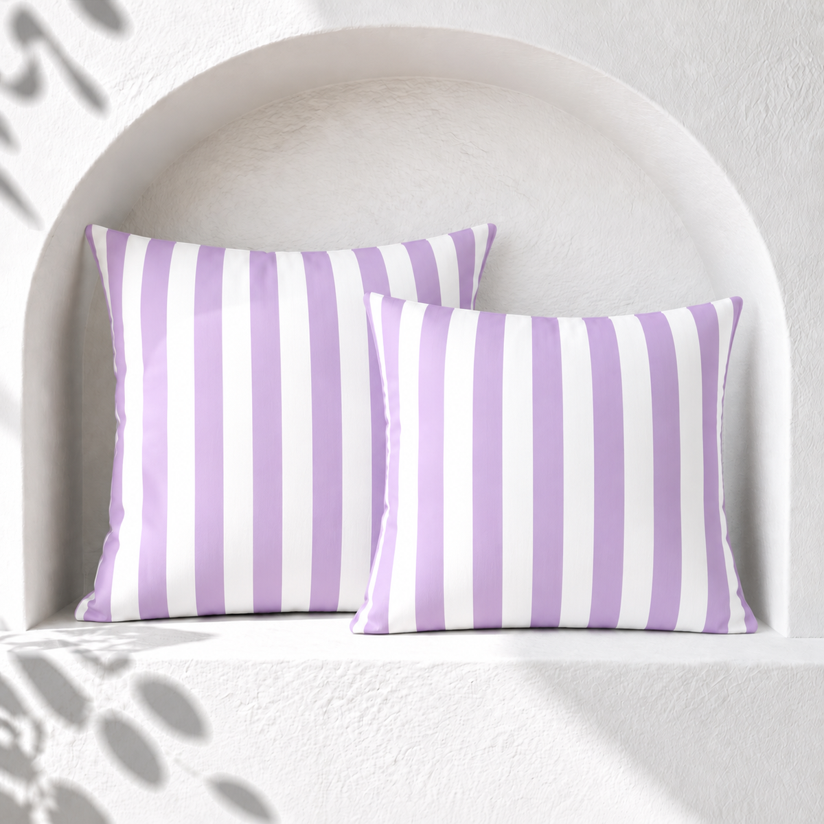 Two purple and white striped weatherproof outdoor cushion covers styled in a white arched Santorini niche