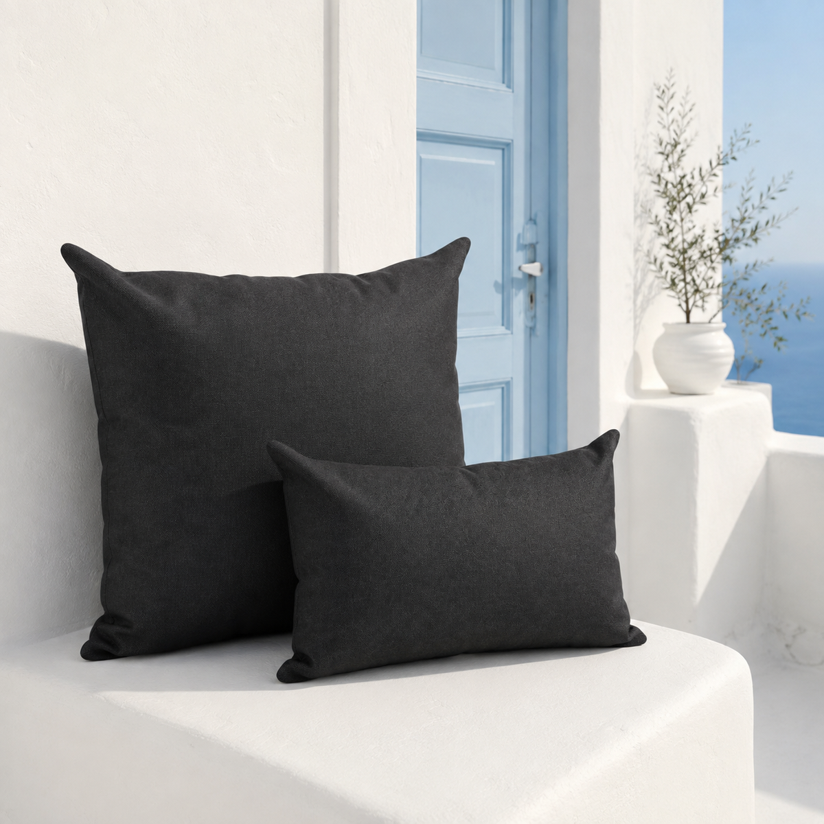 Santorini black weatherproof outdoor square and lumbar cushions styled on a white Santorini terrace with pale blue door