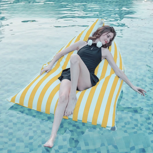 Aussie Waterproof Floating Triangle Beanbag Cover 100x140 in bold yellow and white vertical stripe, shown floating in a pool with a person relaxing on it.