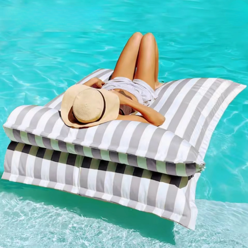 Product photo of the Big Bertha floating beanbag lounger cover in light grey and white stripe, shown floating on clear pool water with detachable pillow.