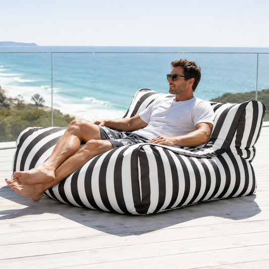 Black and white striped Big Chill King weatherproof outdoor bean bag lounger in a coastal setting