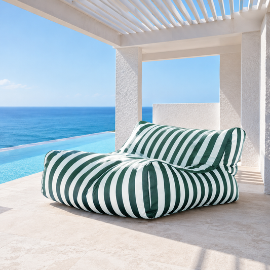 Dark green and white striped Big Chill King weatherproof outdoor bean bag lounger in a coastal setting