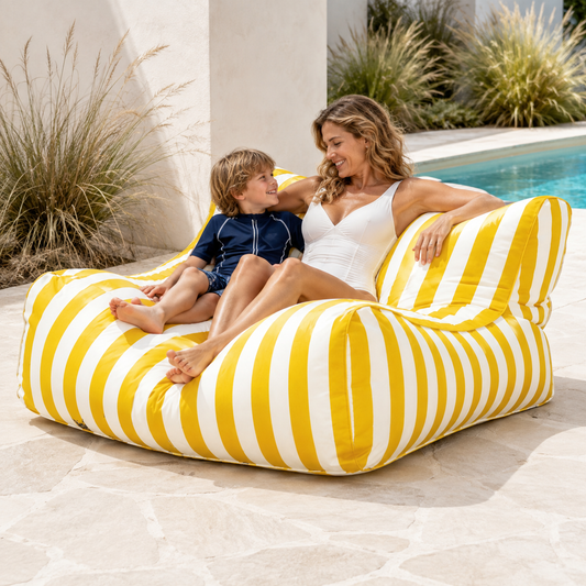 Yellow and white striped Big Chill King weatherproof outdoor bean bag lounger in a coastal setting