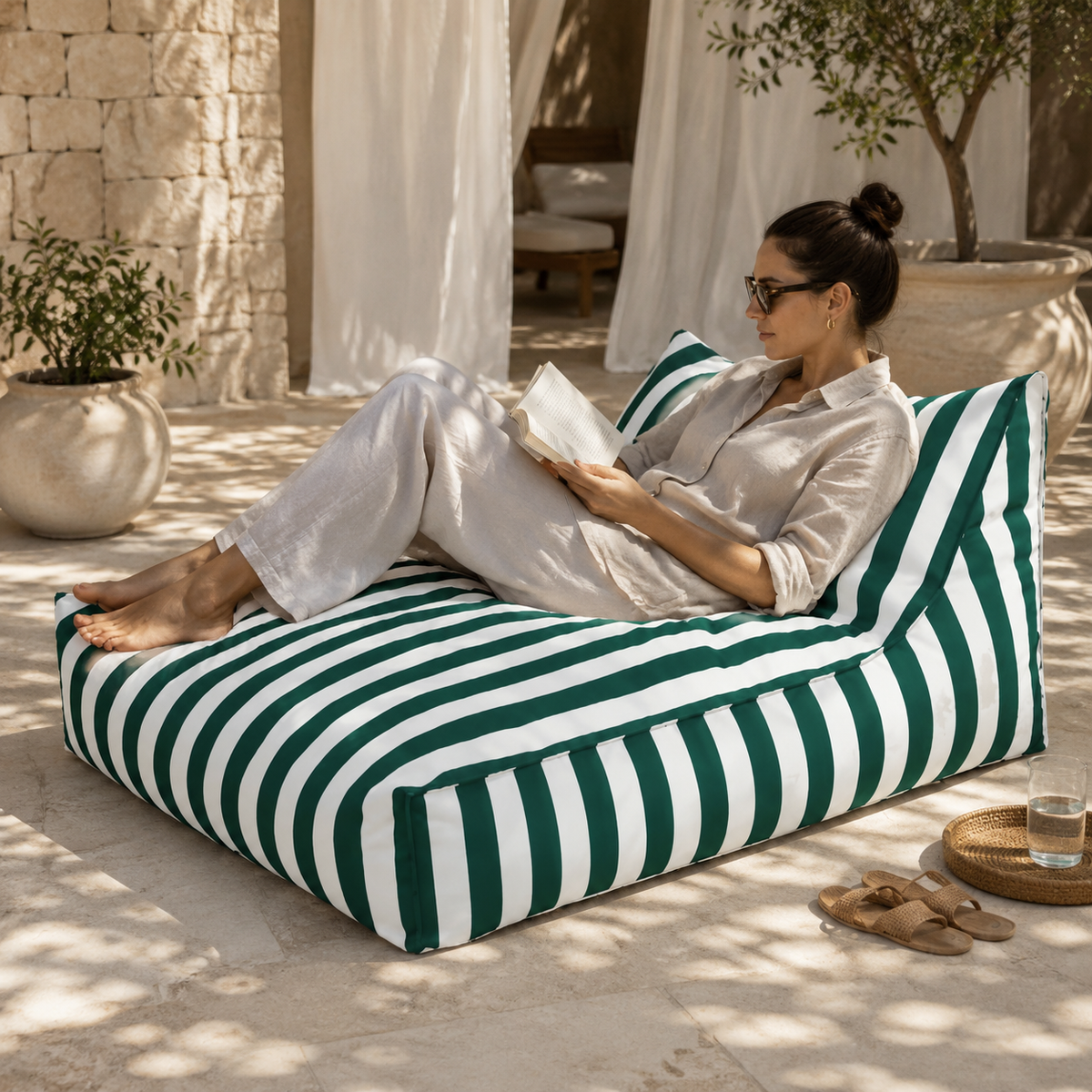 Green and white striped Big Chill weatherproof bean bag lounger with a woman reading in an elegant boutique resort cabana.
