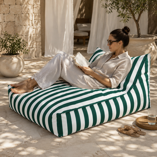 Green and white striped Big Chill weatherproof bean bag lounger with a woman reading in an elegant boutique resort cabana.