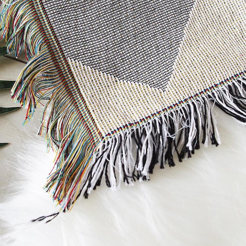 Close-up of the Coastal Picnic Rug showing the Coastal Geo jacquard weave and tassel trim.