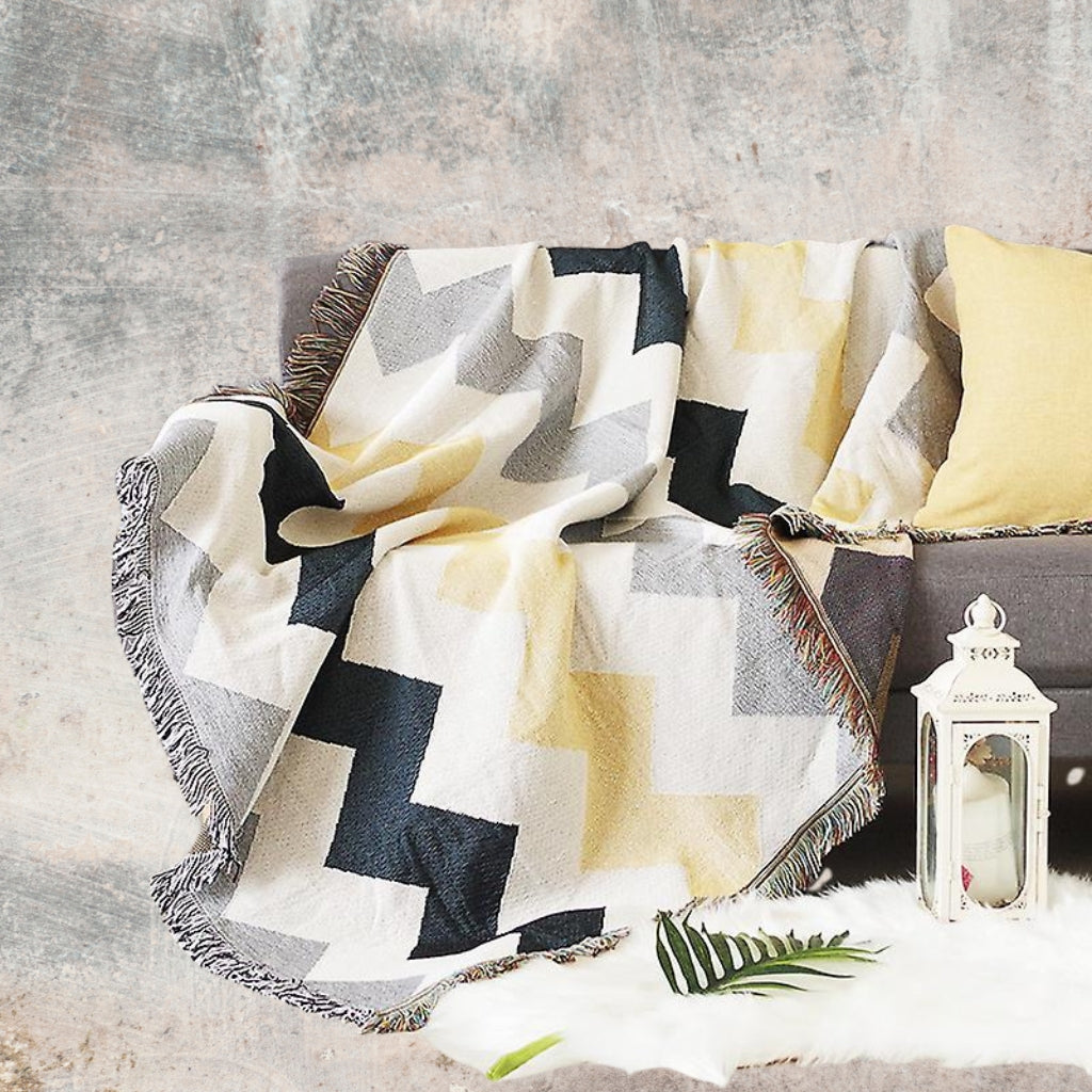 Coastal Picnic Rug in the Coastal Geo pattern, jacquard-woven cotton with tassel edging, shown draped for outdoor or indoor use.