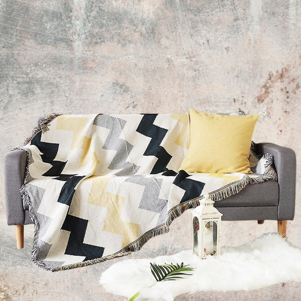 Lifestyle image of the Coastal Picnic Rug in the Coastal Geo pattern displayed on a sofa in a coastal-style living room.