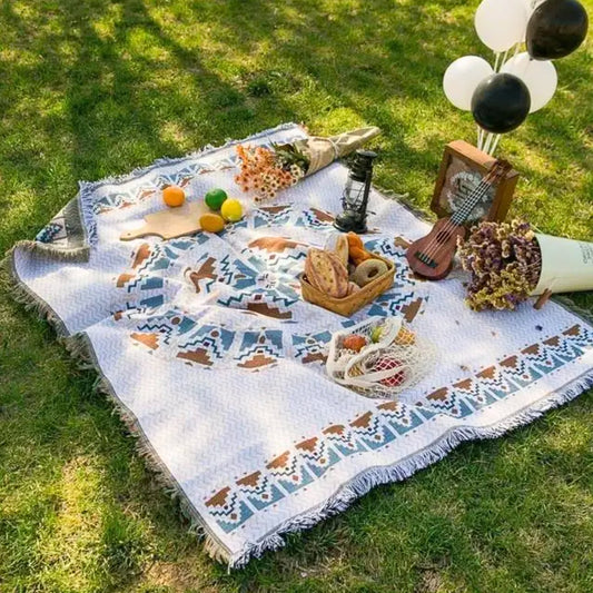 Lifestyle image of the Coastal Picnic Rug in the Scandi Woven pattern displayed on grass with picnic food and accessories