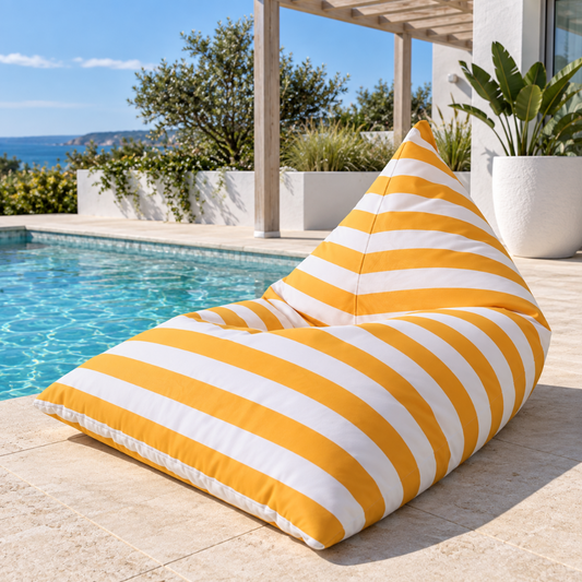 Yellow and white striped Hamptons outdoor triangle beanbag beside a coastal home swimming pool.
