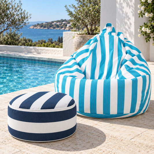 Navy and white stripe outdoor inflatable ottoman styled beside a pool and a sky blue outdoor teardrop beanbag in an outdoor entertaining area.