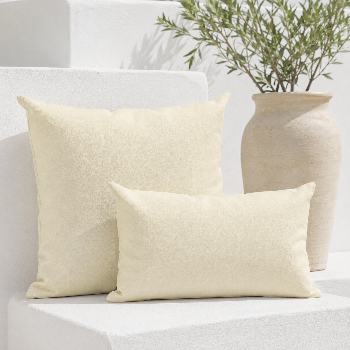 Santorini cream weatherproof outdoor square and lumbar cushions styled on a bright white Mediterranean bench