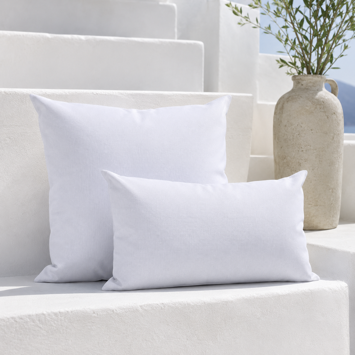 Santorini white weatherproof outdoor square and lumbar cushions styled on a bright white Mediterranean bench