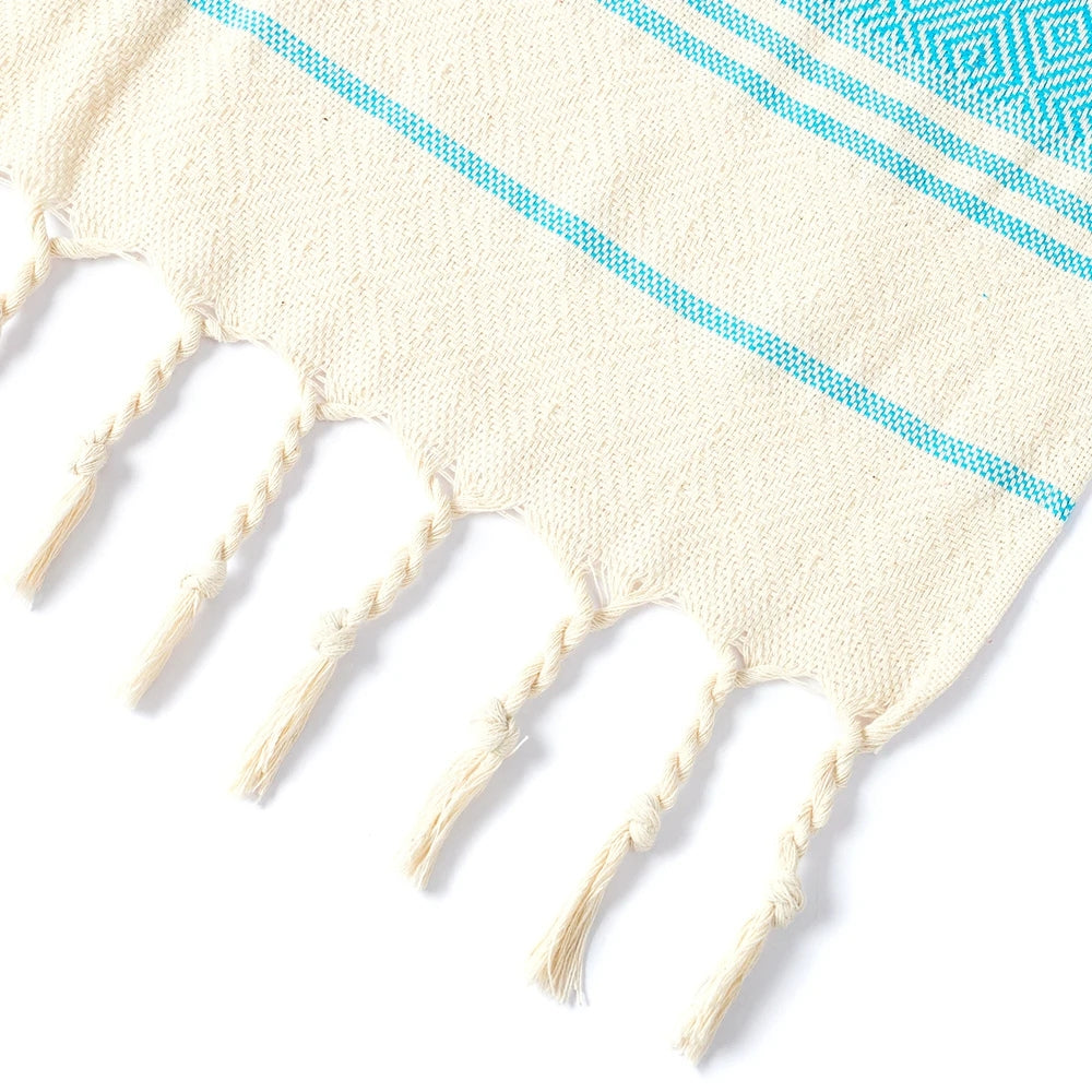 Close-up of cream tassel edging on blue Turkish tassel towel, showing cotton threads and weave.