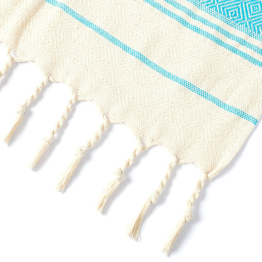 Close-up of cream tassel edging on blue Turkish tassel towel, showing cotton threads and weave.