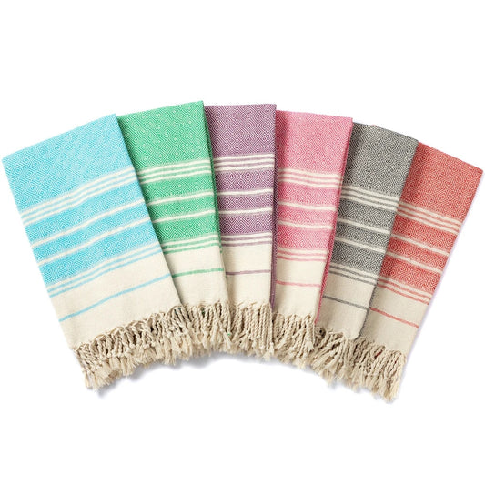 Group arrangement of coloured Turkish tassel towels laid out together, showing pattern, texture and tassel edges.